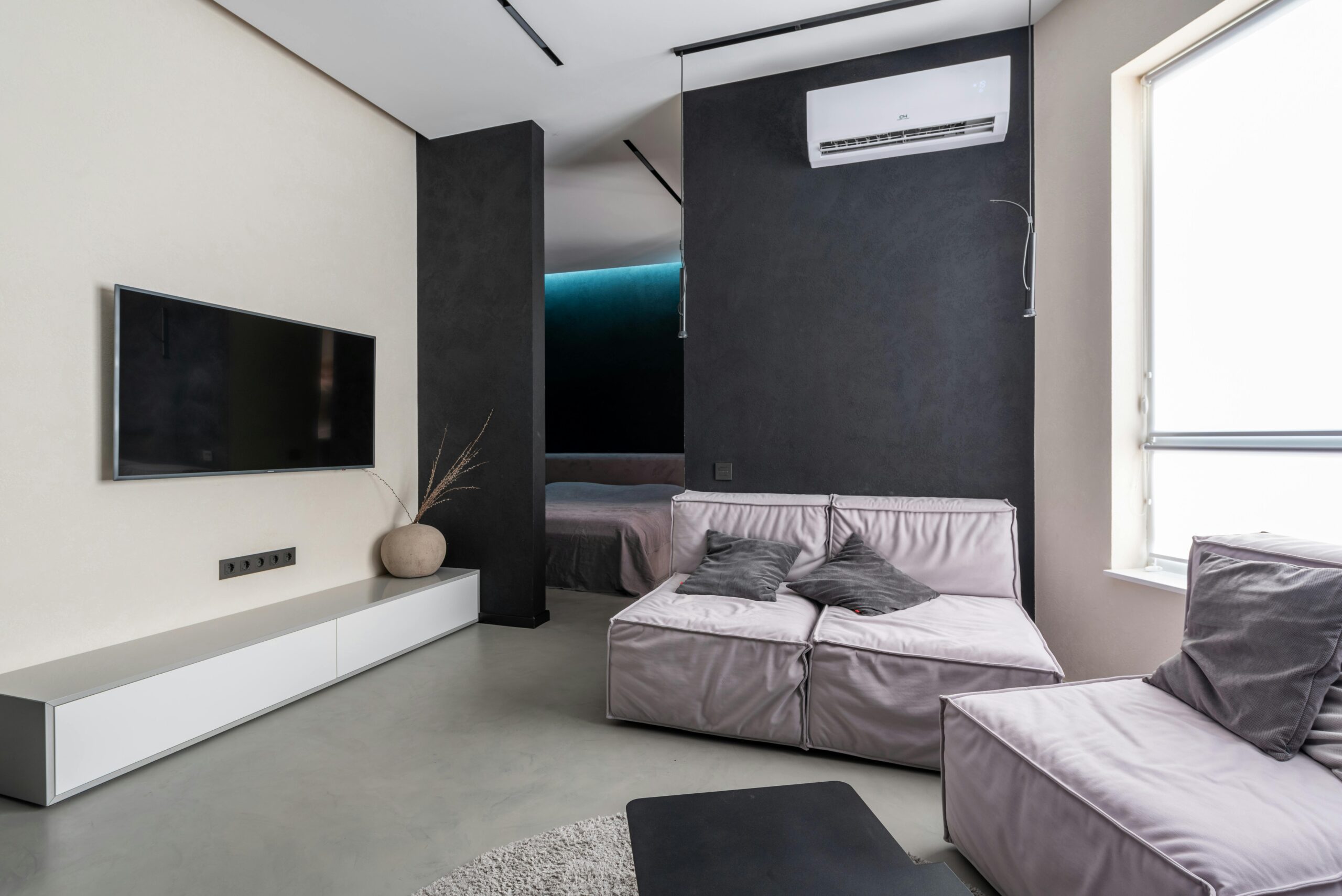 Contemporary living room with sleek furniture, TV, and air conditioning in a modern apartment.